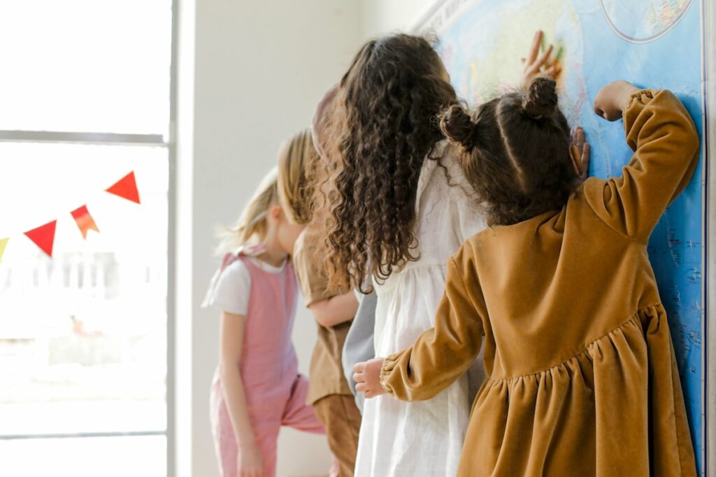 A few kids with their backs turned to the camera working on a panting on the wall.