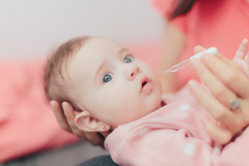 A baby getting iron drops.