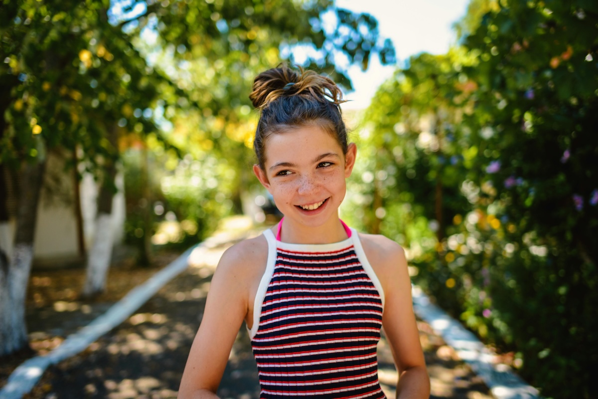 An adult person smiling with green trees in the background