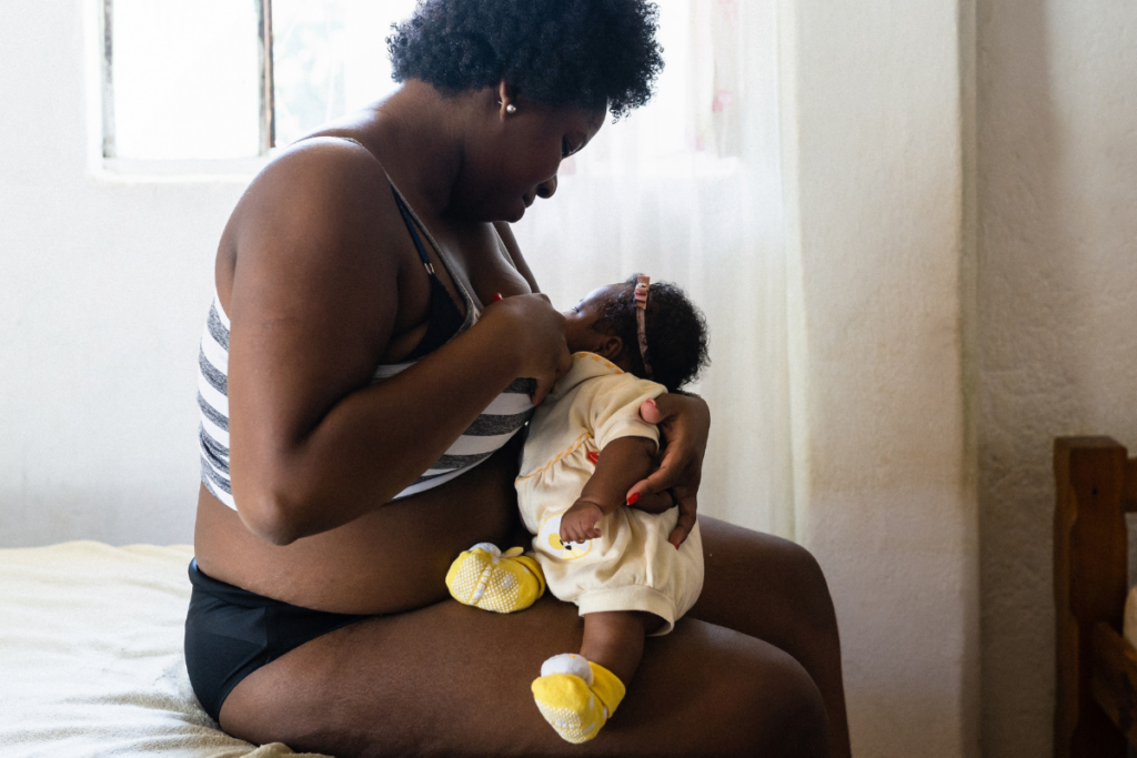 Mother breastfeeding her newborn in bed.