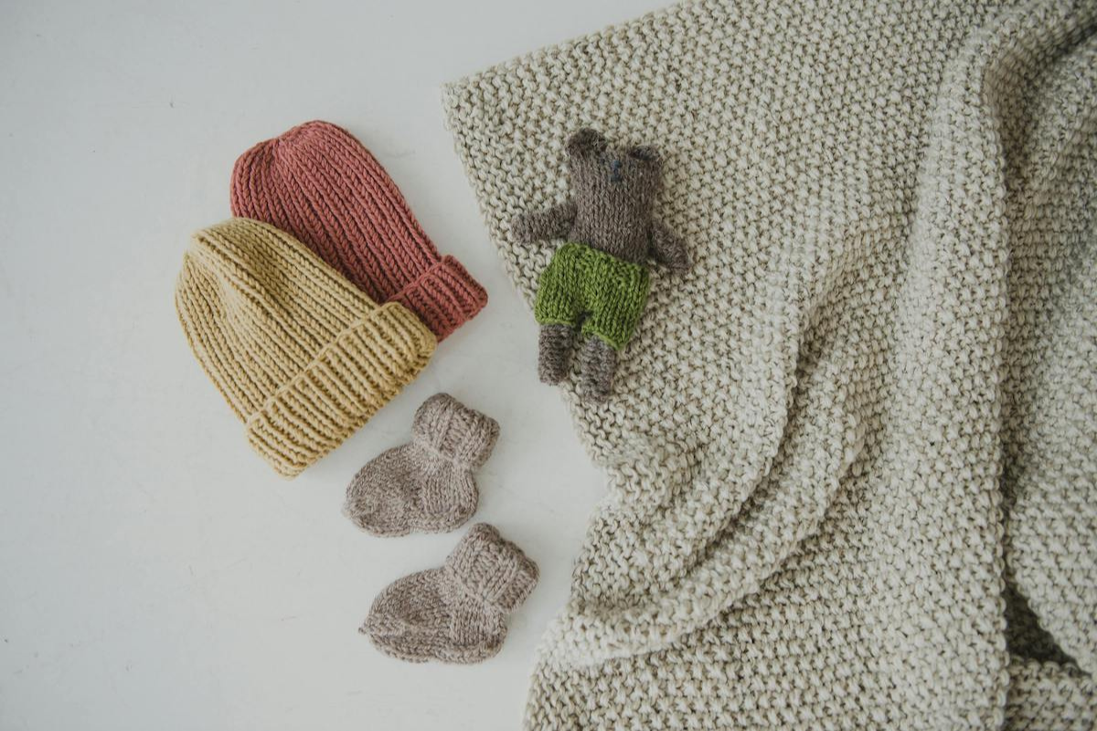 Newborn accessories like socks, beanies, a blanket and a teddy.
