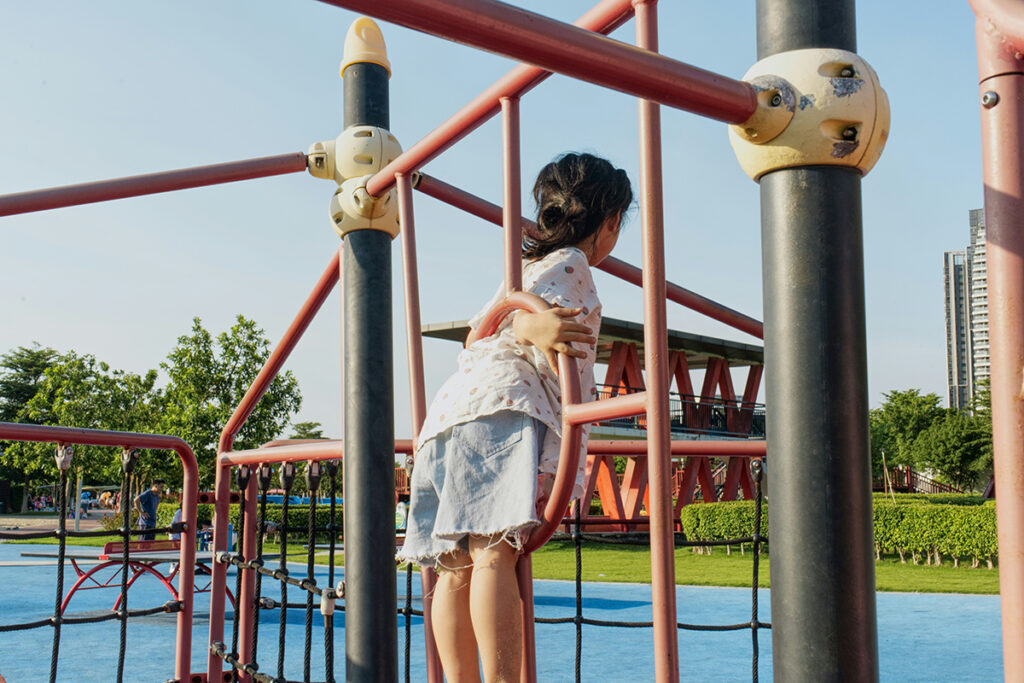 A child playing on an outdoor jungle gym.