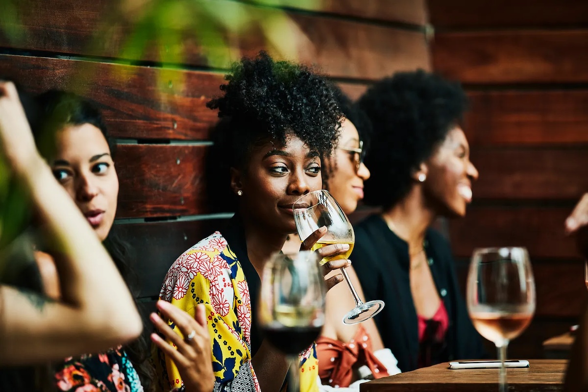 A woman sips a glass of wine with friends.