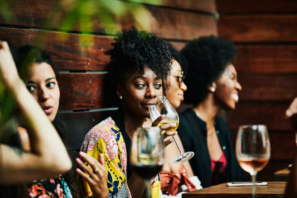 Woman enjoying drink with friends at poolside bar.