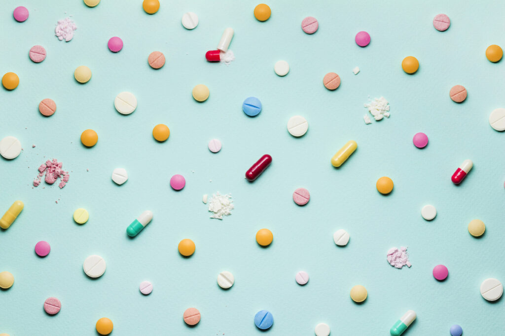 An array of different pills on a blue background.