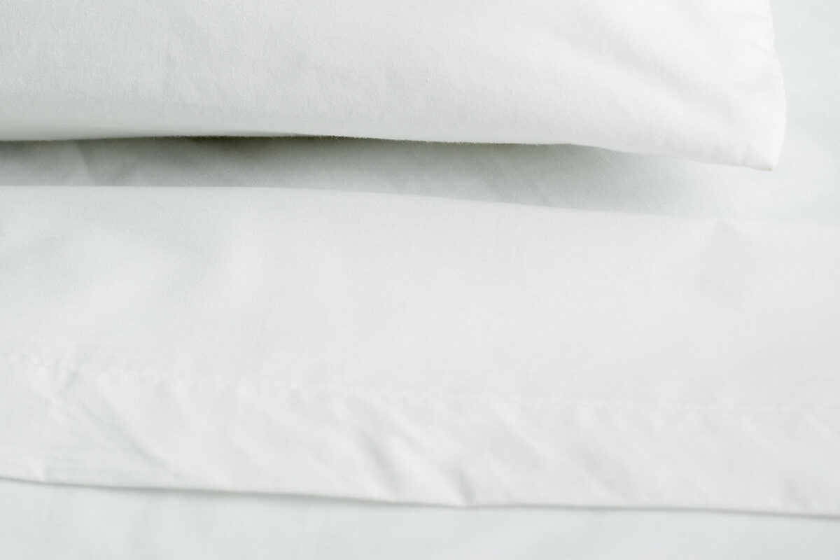 A stack of white pillows on the corner of a bed.