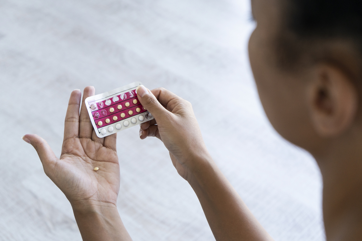 Close-up of young woman's hand holding birth control pills