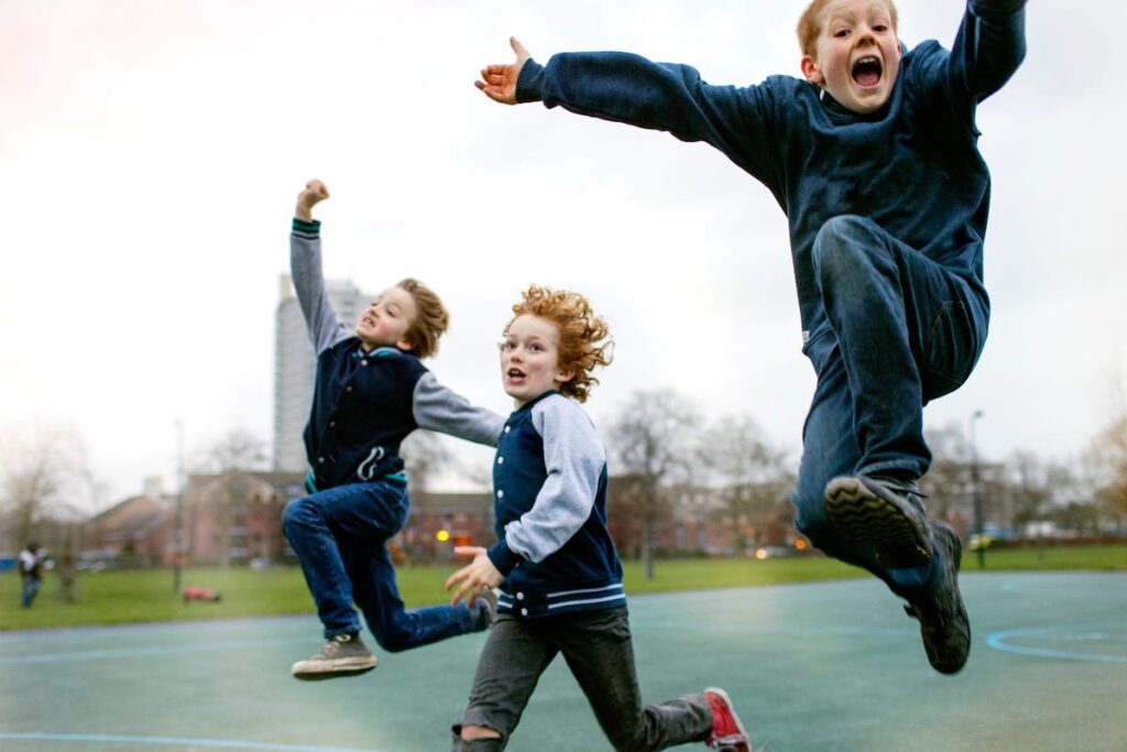 Three kids running and leaping outside.