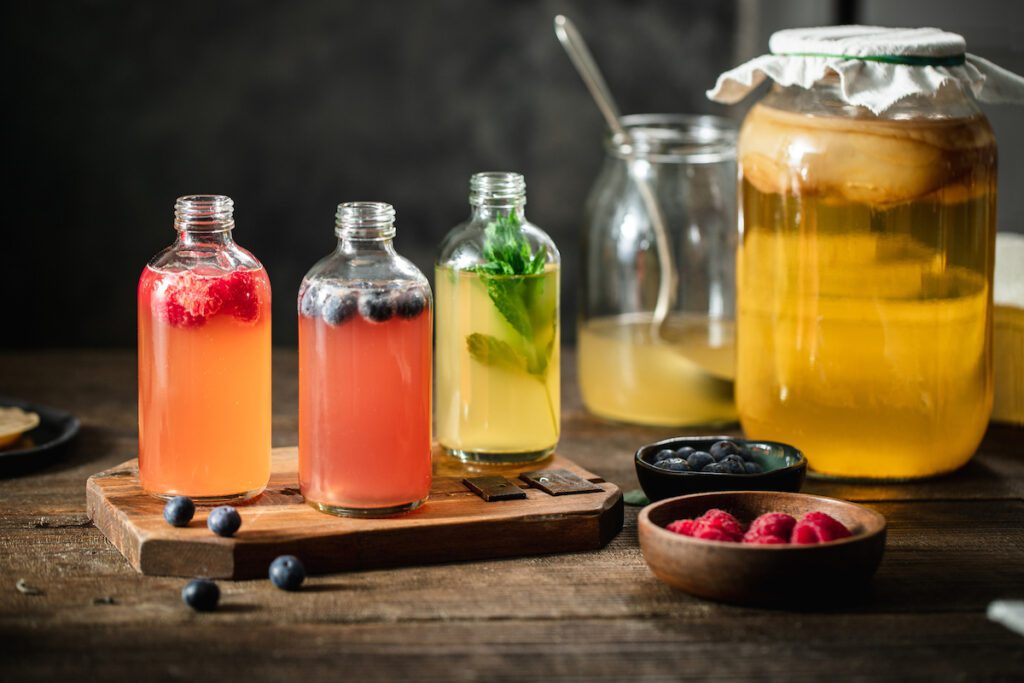 Bottles of kombucha tea are arranged on a wood board.