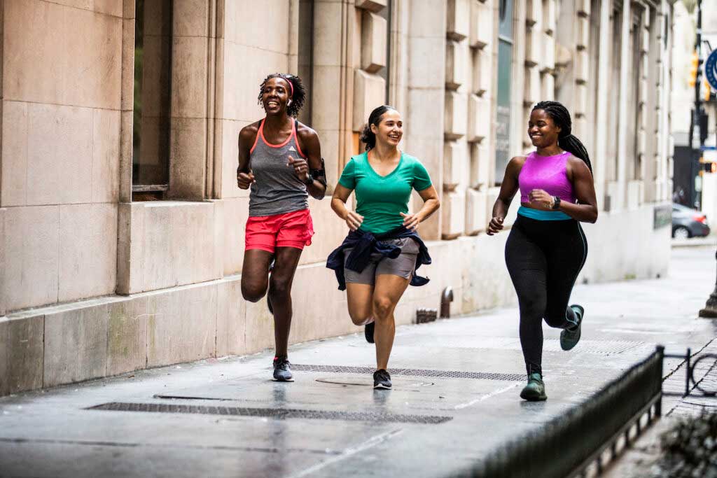 Group of friends runs down a city sidewalk.