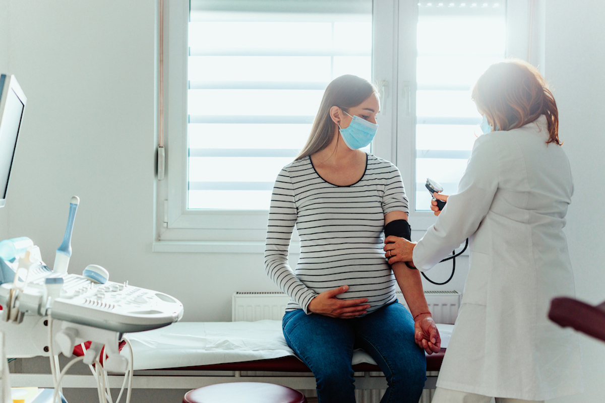 A pregnant person has her blood pressure taken at a doctor's appointment.