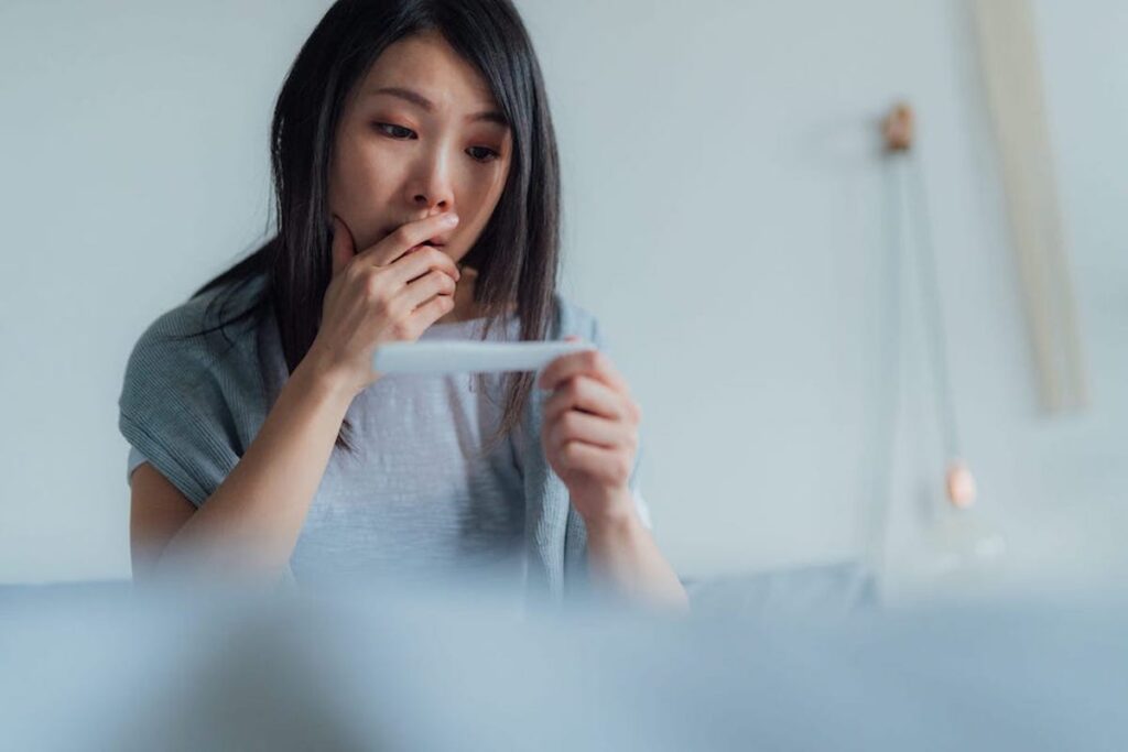 A woman looks concerned while holding a pregnancy test.