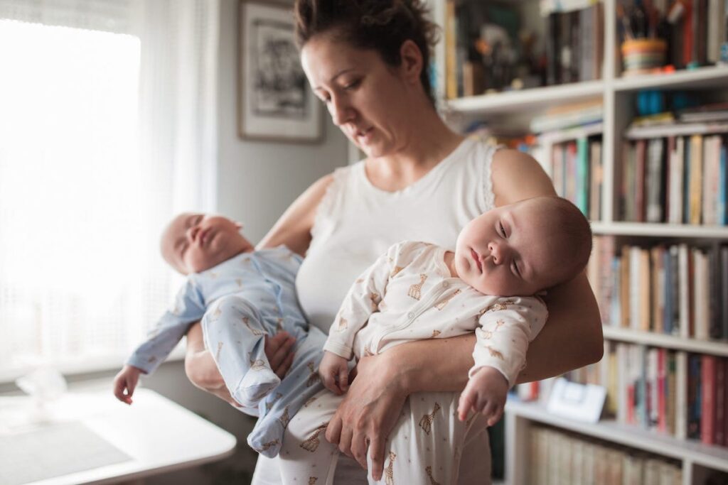 A parent holds two sleeping babies.