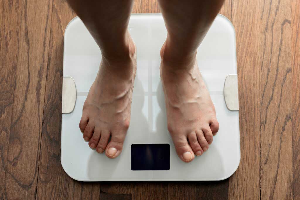 A top down view of feet standing on a white digital bathroom scale.