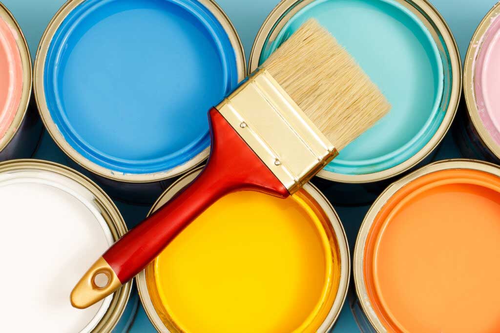 Paint cans filled with pink, blue, green, orange, white, and yellow paint, with a paint brush on top.