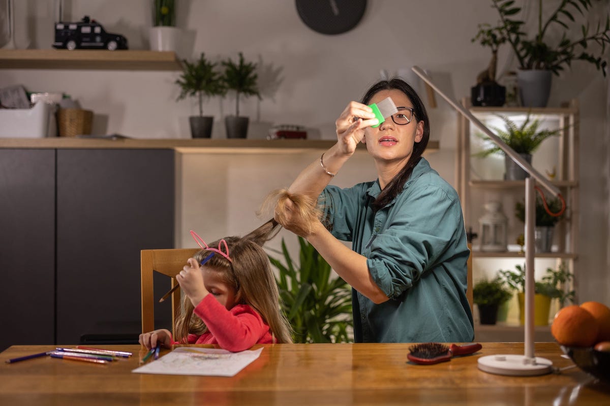 A parent combs a child's long hair with a lice comb, and examines the comb in the light.