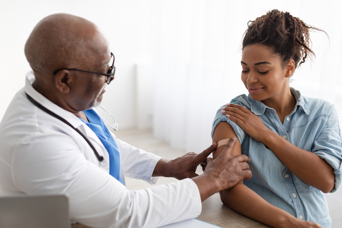 A doctor placed a bandaid on the arm of a pregnant person after administering a vaccination.