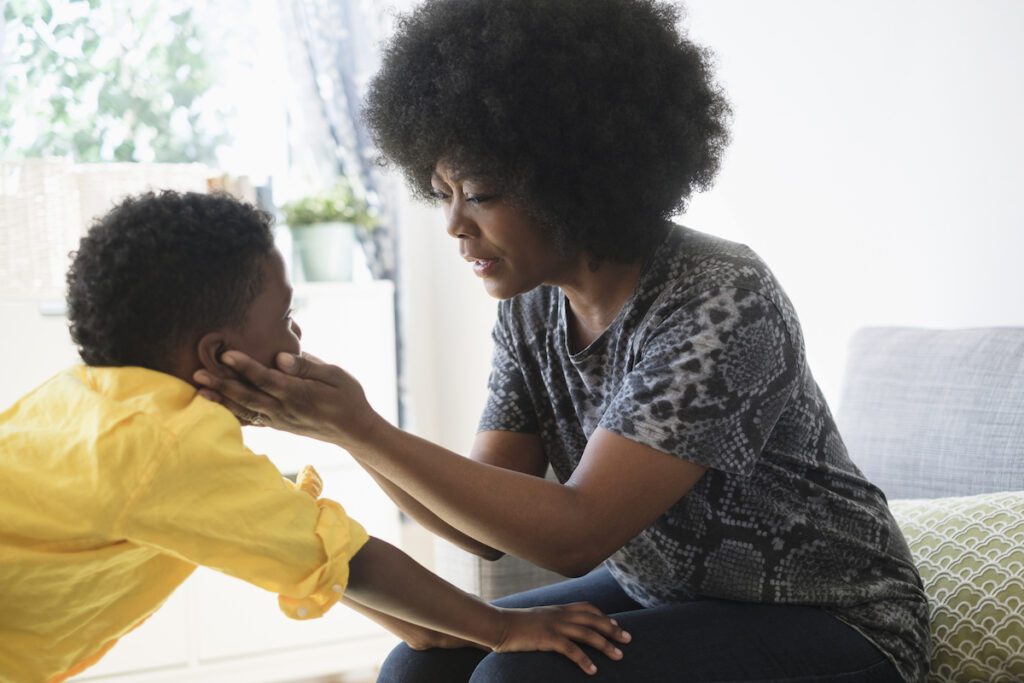 A mother cups her child's face during a hard conversation.