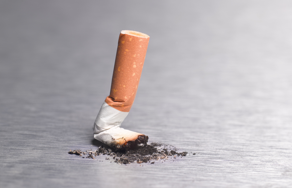 A cigarette butt stubbed out on a stainless steal surface.