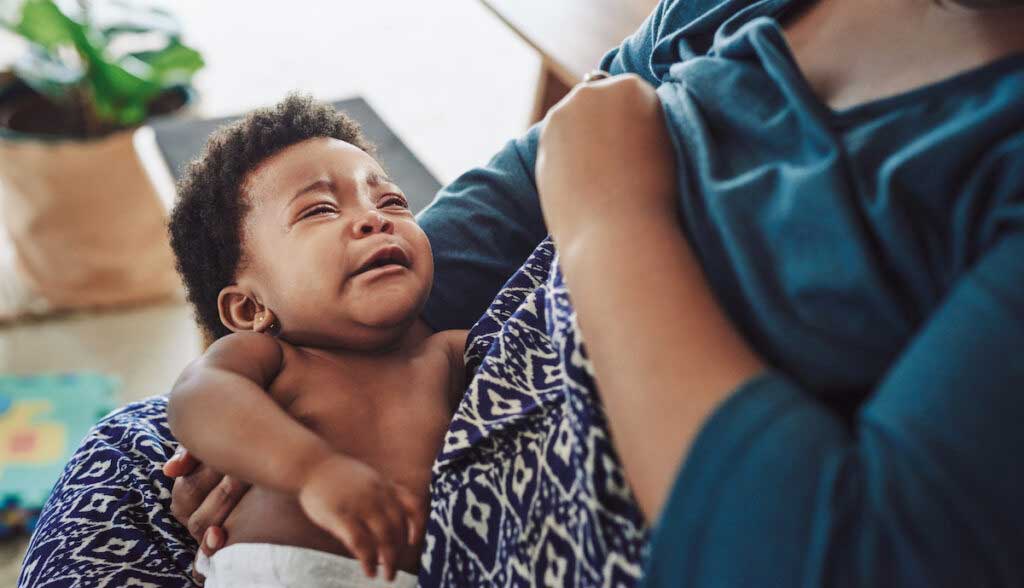 A mother tries to breast feed while her baby cries.