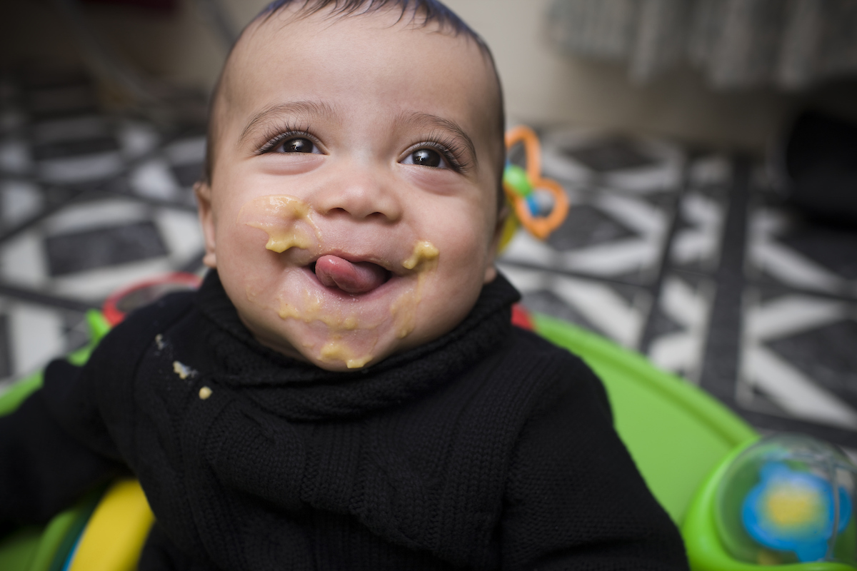 A baby sticks out their tongue and smiles.