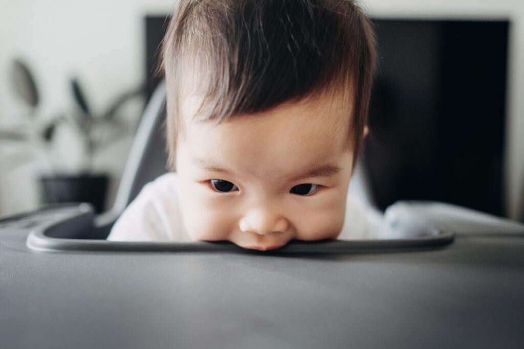 Baby bites a highchair table.