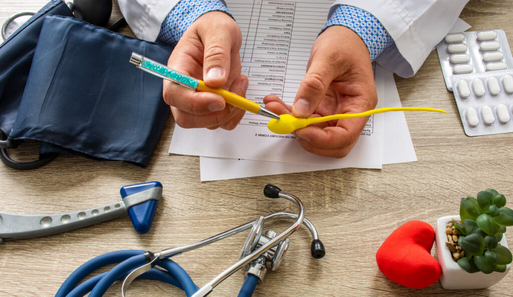 During a consultation, a doctor shows a model of sperm and uses a pen to indicate different parts.