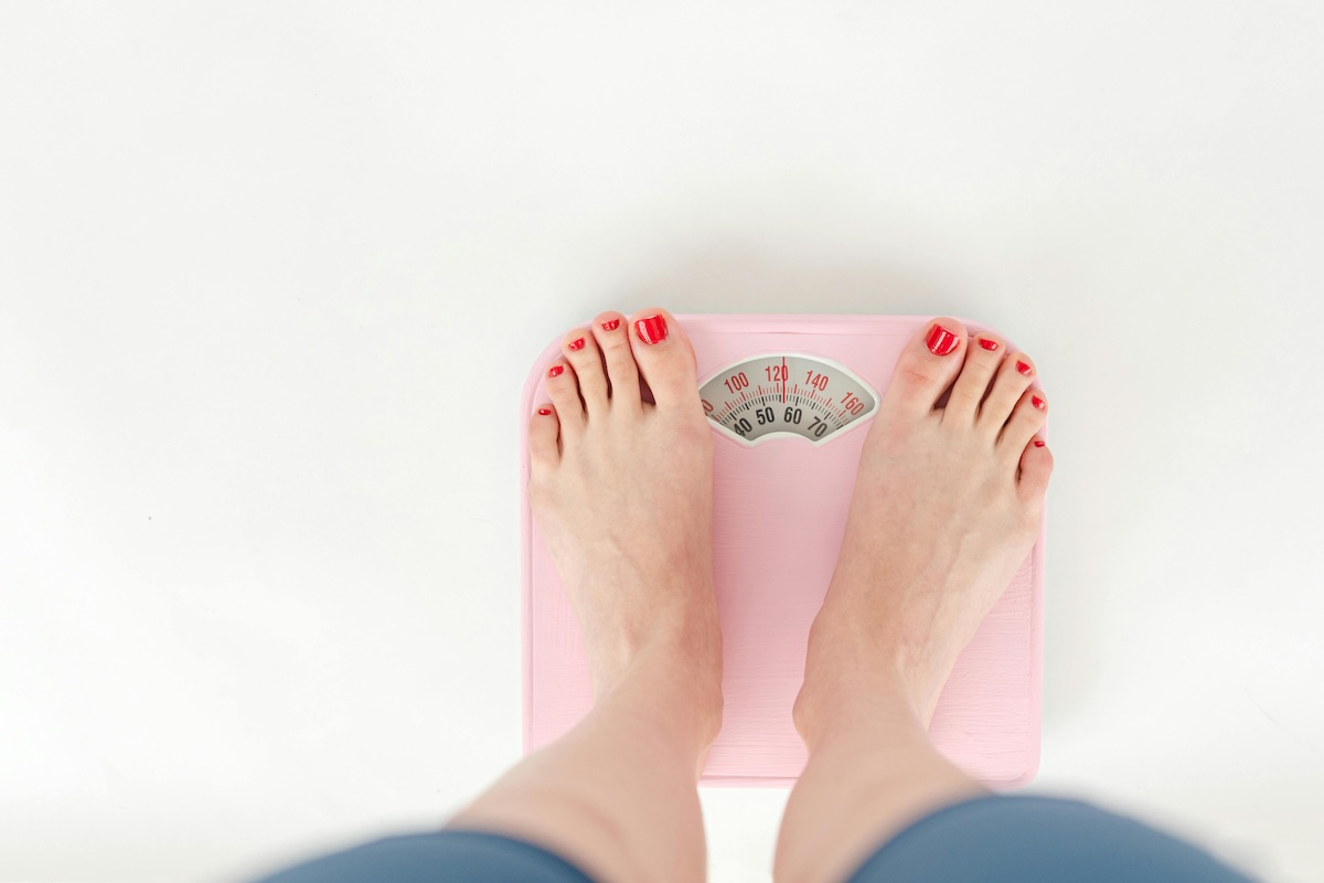 Feet standing on a pink weight scale.