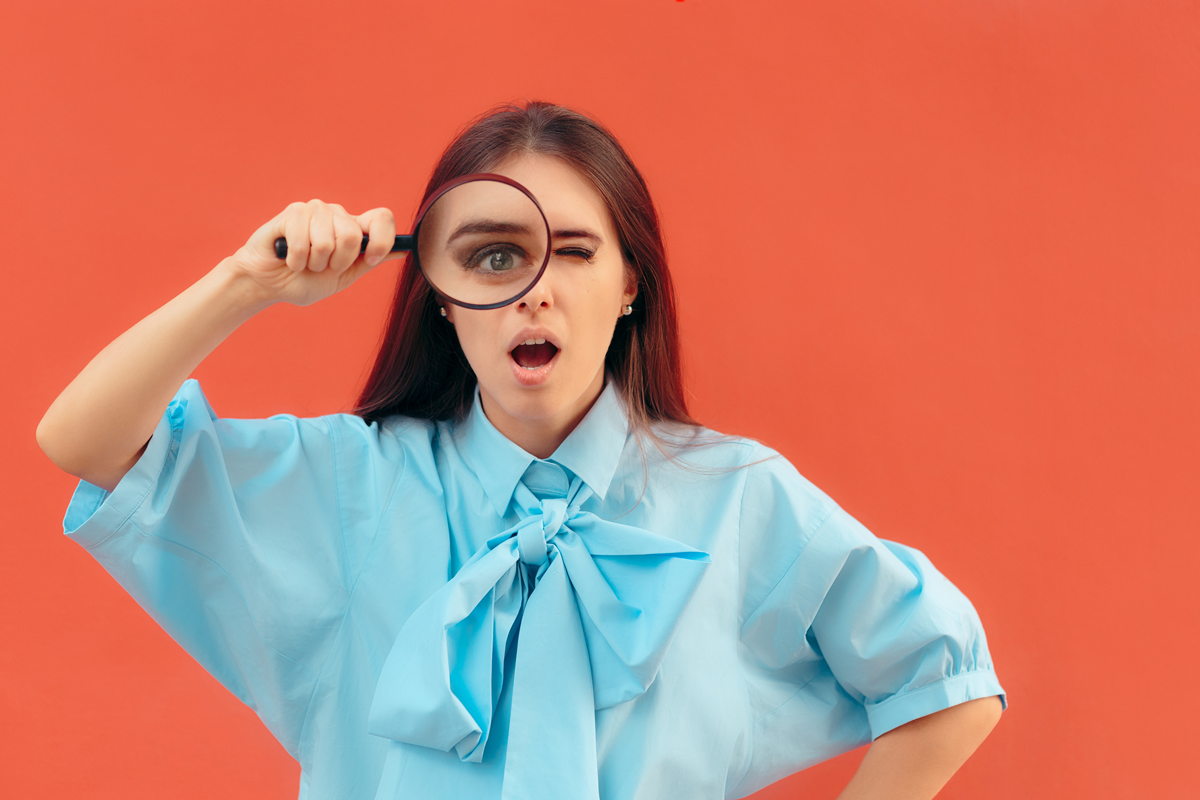 A judgemental person holding a magnifying glass looks on, horrified.