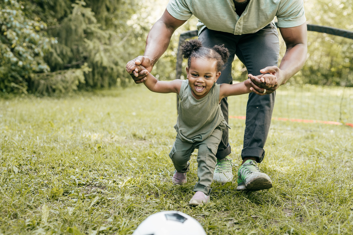 A toddler has fun playing outside with a parent.