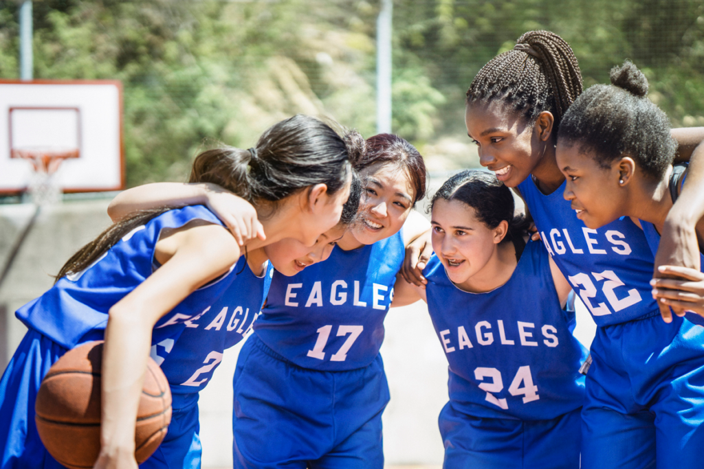 A group of teens huddles together during a basketball game.