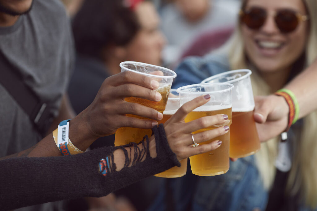 Friends do cheers with plastic cups of beer.