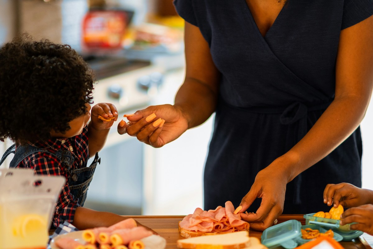A parent makes lunch for their kids.