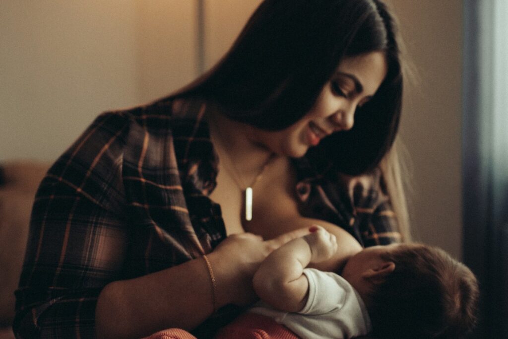 A parent breastfeeds a baby during a happy moment.
