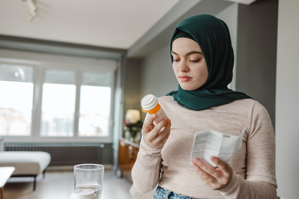 A person reads a pamphlet while looking at a bottle of antibiotics.