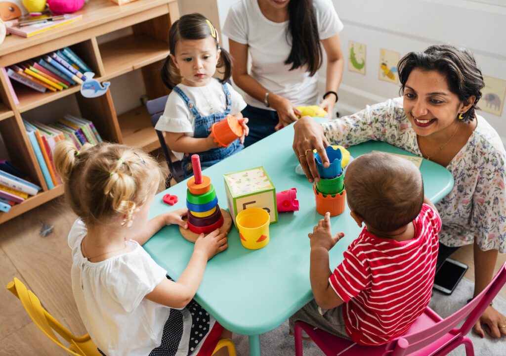 Young children playing with teacher in the classroom