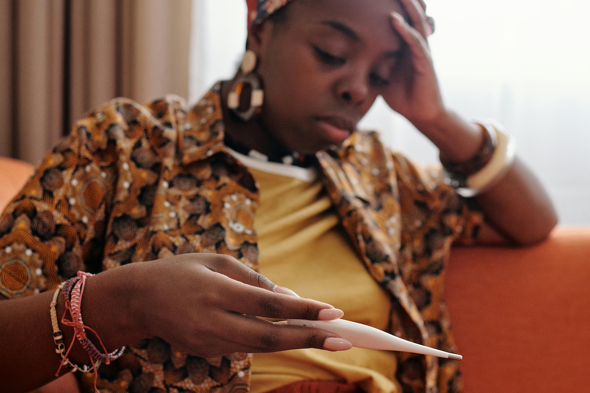 Person with fever looking at thermometer