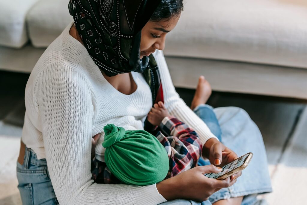 Parent breastfeeds baby while looking at phone