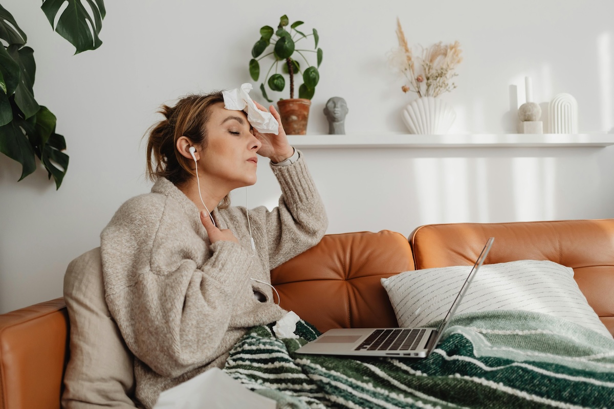 Person sitting on couch holding towel to head