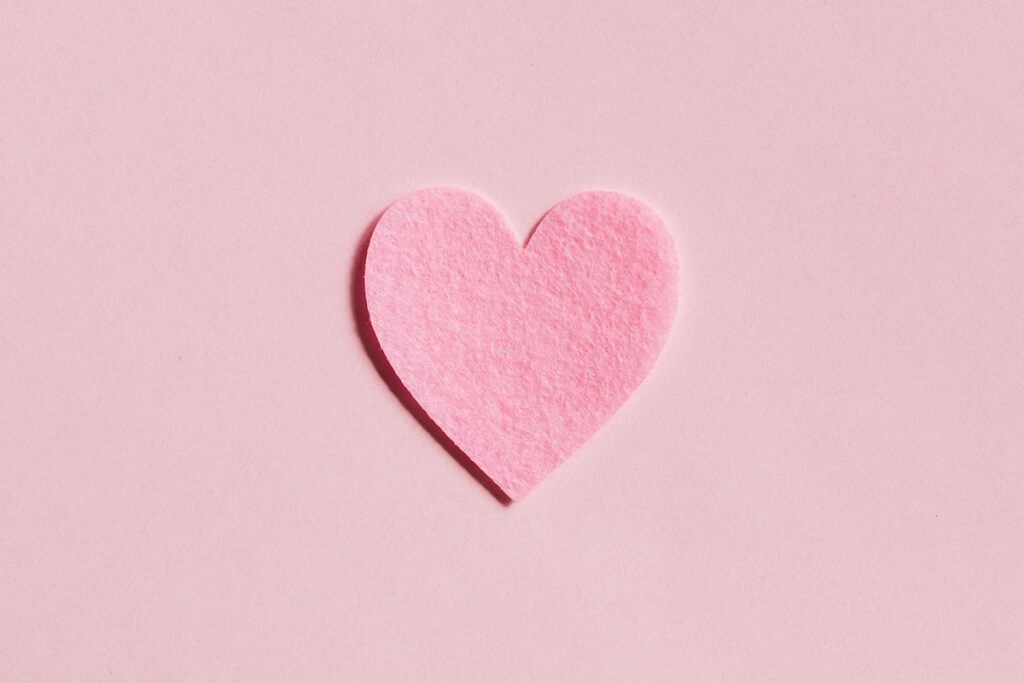 Pink felt heart on pink background