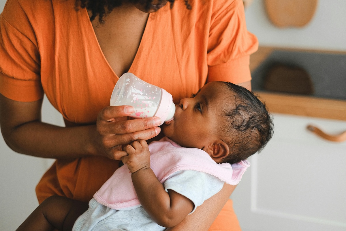 Baby in parent's arms having a bottle