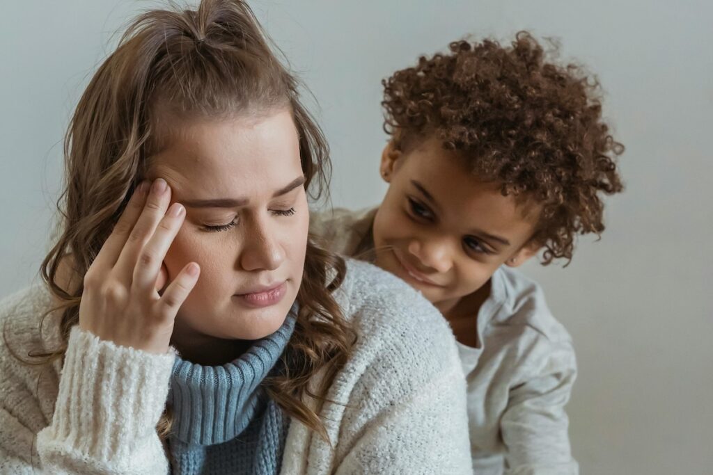 Child behind stressed looking parent