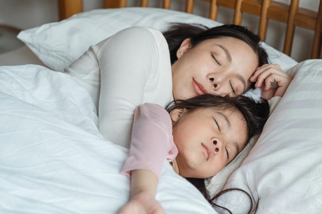 Parent and child asleep together in bed