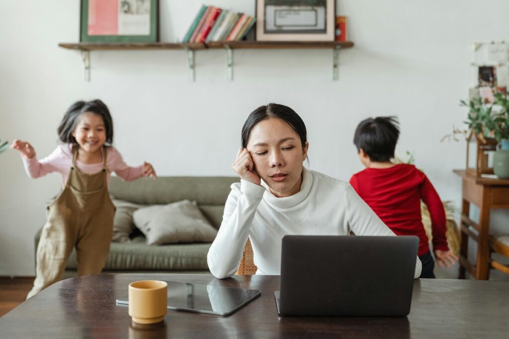 Tired looking parent with two children playing in background
