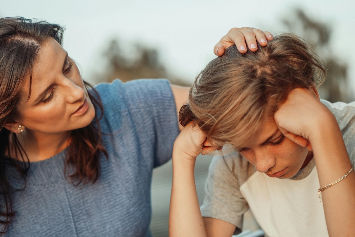 A parent talking and consoling a big child while placing hand on the head