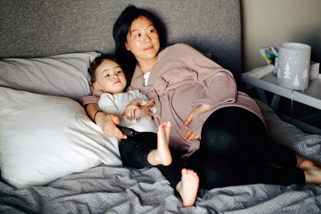 Adult snuggling toddler in bed