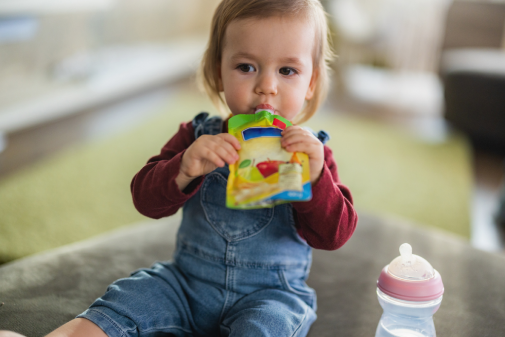 Young toddler eating fruit puree in a pouch.