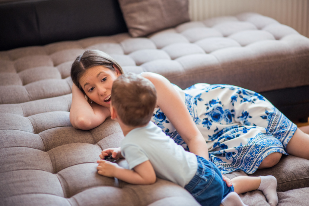 A parent talking to a toddler by the sofa.