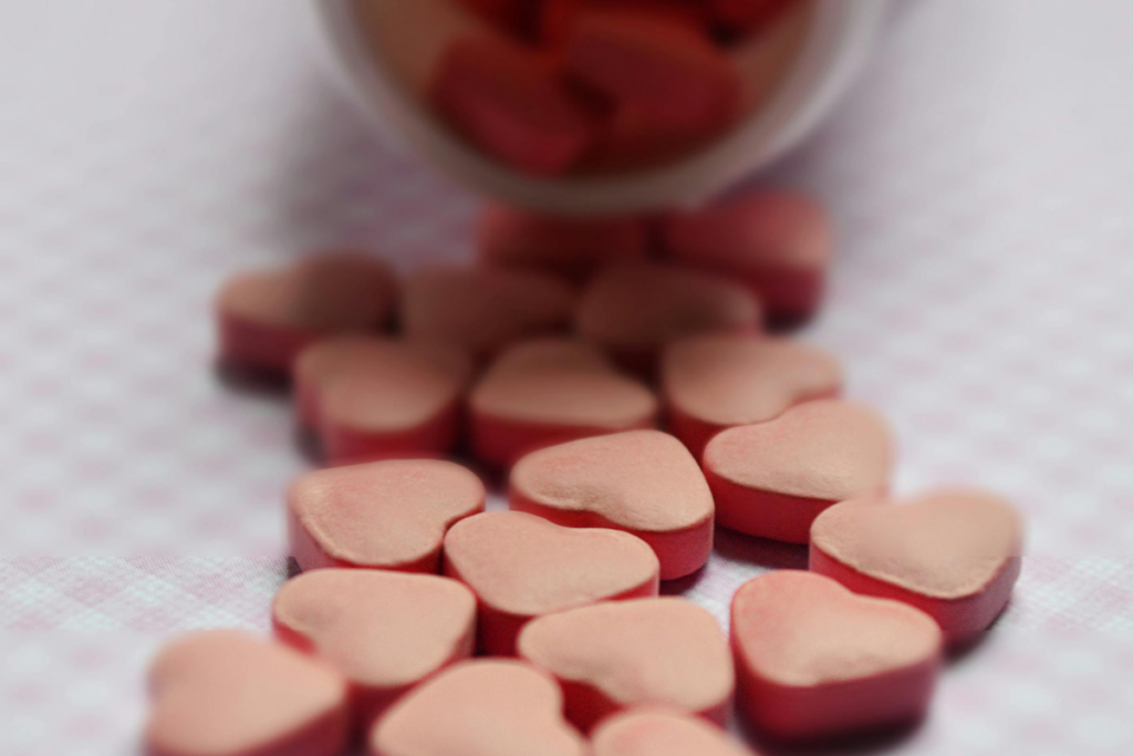 Heart shaped red pills coming out of a pill box