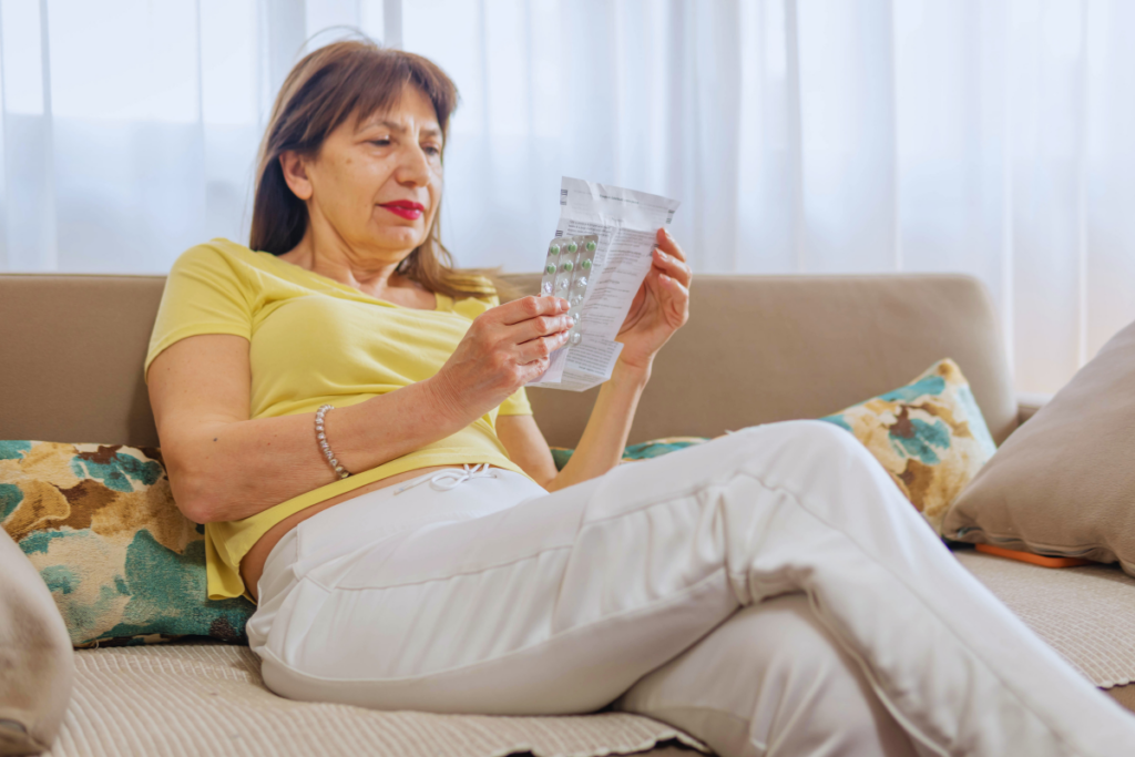 A person reading a prescription and holding pills.